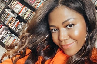 A selfie of Amerie with a bookshelf behind her.