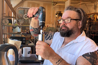 Guy using a drill to grind coffee.