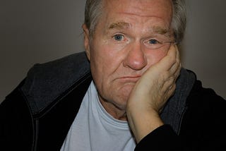 Middle-aged man with his hand on his face, looking bored