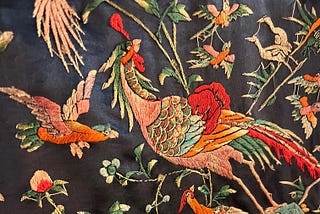 Colorful birds and flowers embroidered on black silk.