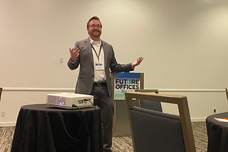 Me speaking at an HR conference, gesturing to the audience with both hands raised