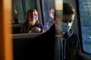 Young people on train wearing face masks.