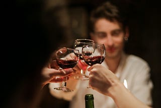 Three people toasting with wine glasses around a candlelit dinner table.