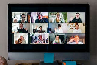 Friends waving to each other during a large video conference call on a computer screen.