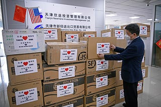 A worker arranges boxes of medical supplies, including 1,000 KN95 masks, 2,000 surgical masks, 100 protective suits and so on