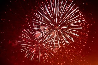 A photo of fireworks against a red night sky.