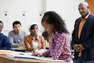 Black girl reading in front of her classmates at school.