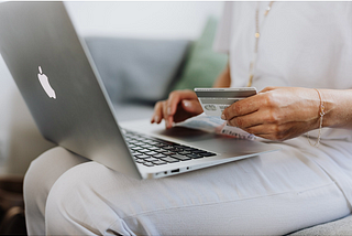 Person holding credit card while on laptop.