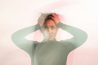 Photo of a woman looking frustrated with both hands on the side of her head