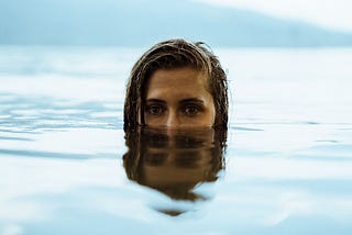 Woman almost entirely underwater, with her face from the nose up above the surface.