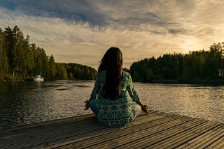 Woman sat meditating in front of scenic view