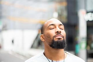 Young Black man closing his eyes with a peaceful expression.