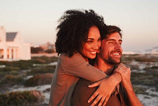 Multiracial couple embracing while watching a sunset.