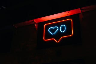A photo of Instagram’s like tooltip with 0 hearts, recreated in neon against a black background.