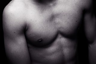 A monotone picture of a shirtless young man with a black background