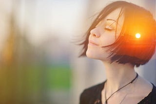 A young, brunette, short-haired woman meditating outdoors with eyes closed, combined with photographs of nature, sunrise, or sunset. Body’s wisdom and intuition.