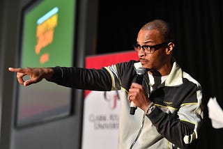 A photo of T.I. onstage pointing with his left arm into the crowd.