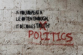 Grafitti on a concrete wall says If you repeat a lie often enough, it comes truth, but the word truth is marked off and replaced with the word politics