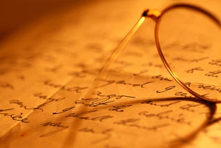 Closeup of glasses on a page scribbled with words.