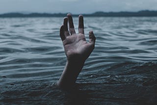 Hand rising out of dark lake.