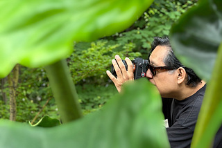 Capturing my partner sneaking up on leafy scenery in the Atlanta Botanical Garden summer before last — it was swelteringly hot and the shade was sublime.