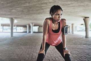 A sweaty young woman takes a break while exercising outdoors.