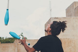 Man in black t-shirt juggling with cones