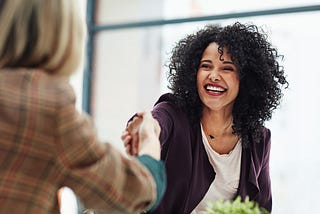 A female job candidate shakes her interviewer’s hand.