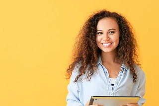 Young woman with tablet computer on yellow background.