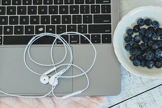 productivity boost work snacks laptop keyboard headphones fluffy pink blanket bowl fresh blueberries white distressed table