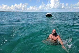 The author being towed behind a sailboat in turquoise, Bahamas water