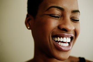 A closeup of a black woman smiling/laughing widely.