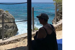 Picture of the author sitting on a ledge, staring at the ocean.