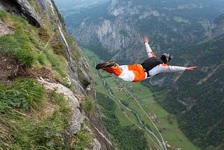 Base jumper diving  down into a valley.