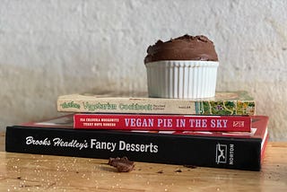 Ramekin of chocolate mousse on top of The Farm Vegetarian Cookbook, Vegan Pie in the Sky, Brooks Headley’s Fancy Desserts