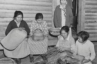 A black and white vintage photo of Choctaw women weaving baskets in the early to mid 20th century.