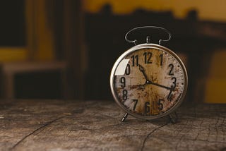 Old small clock sitting on wooden table