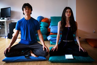 Chris Aimone and Ariel Garten, cofounders of InteraXon, are sitting down in seated positions wearing the Muse headband.