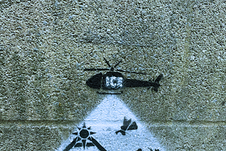 A concrete wall with a painting depicting an ICE helicopter flying above a nativity scene.