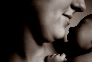 A black and white closeup photo of a mom holding her newborn baby.