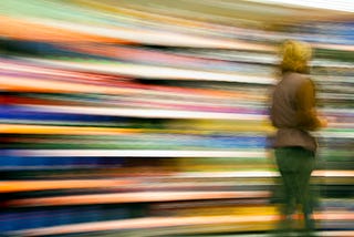 A person walking toward the right side of the pic against a colorful, motion-blurred background.