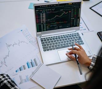 A laptop with an increasing line graph is next to a printed page of an increasing line graph.