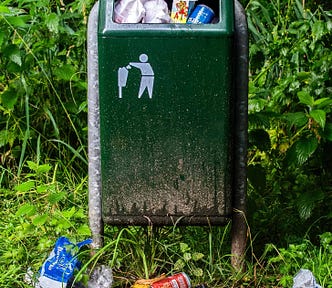 Green trash can with overflowing garbage.