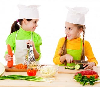 Two girls making salad, cooking the vegetables. Isolated on white