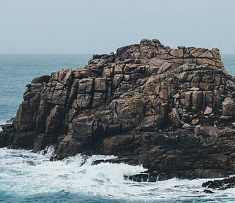 An outcropping of brown rocks against a blue sea