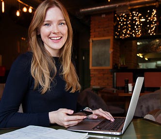 A woman sitting in front of a laptop smiling.