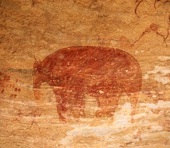 A Mastodon cave painting, depicting a reddish Mastodon on a sand-colored rock wall.