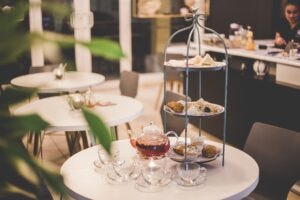 Image of a table laid-out with a tower of sandwiches and cakes for ‘afternoon tea’ to illustrate post