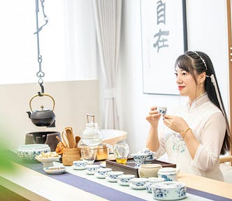 A woman sits in front of a table of tea-related items. Tea ceremonies are popular throughout Asia. The partaking of tea is considered a practice of equanimity. | Source: kimmi jun, Pexels