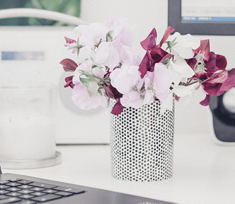 Vase of flowers on desk near laptop